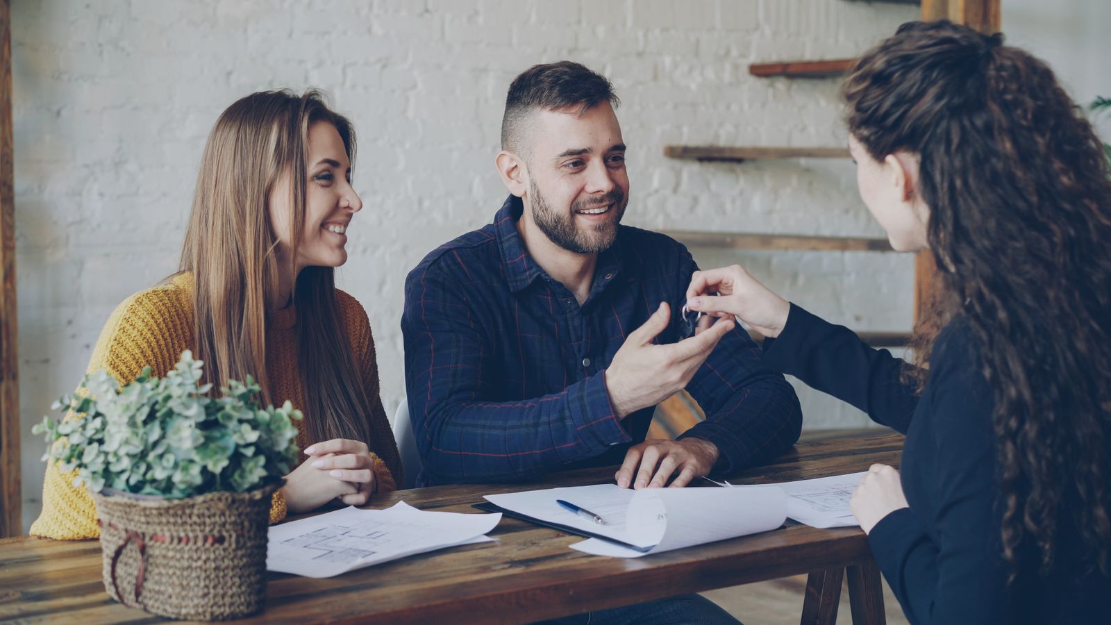 A property professional handing keys to new homeowners during a consultation