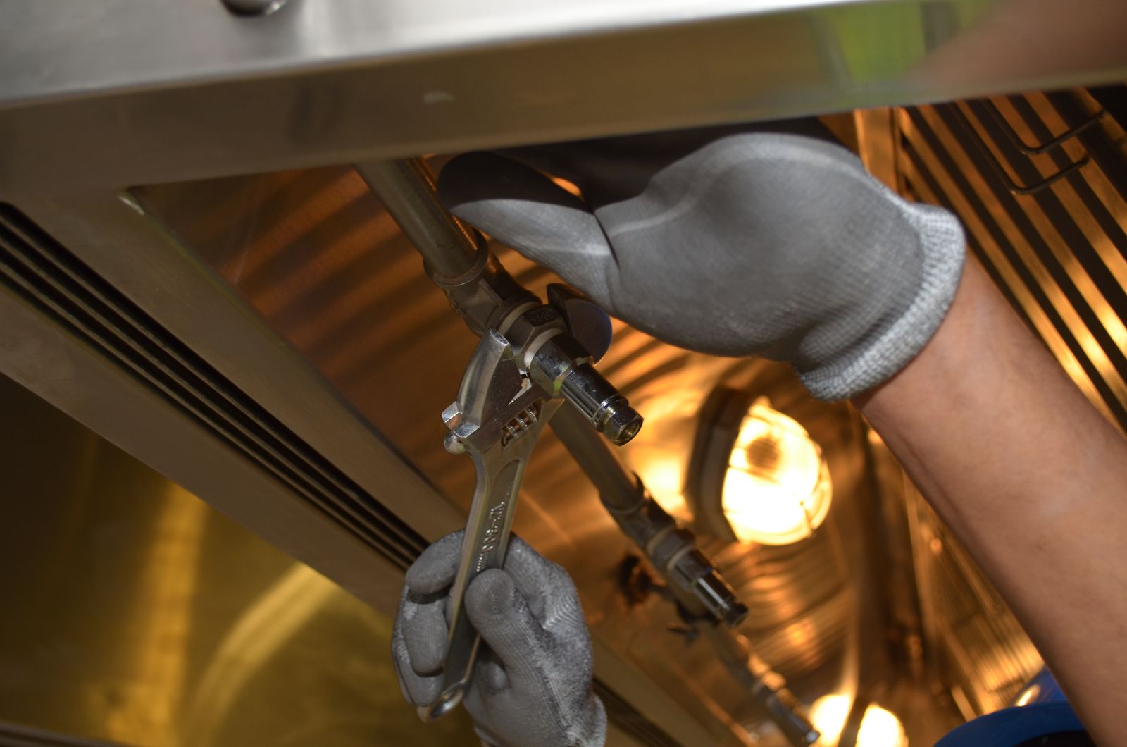 A maintenance technician repairing plumbing beneath a sink