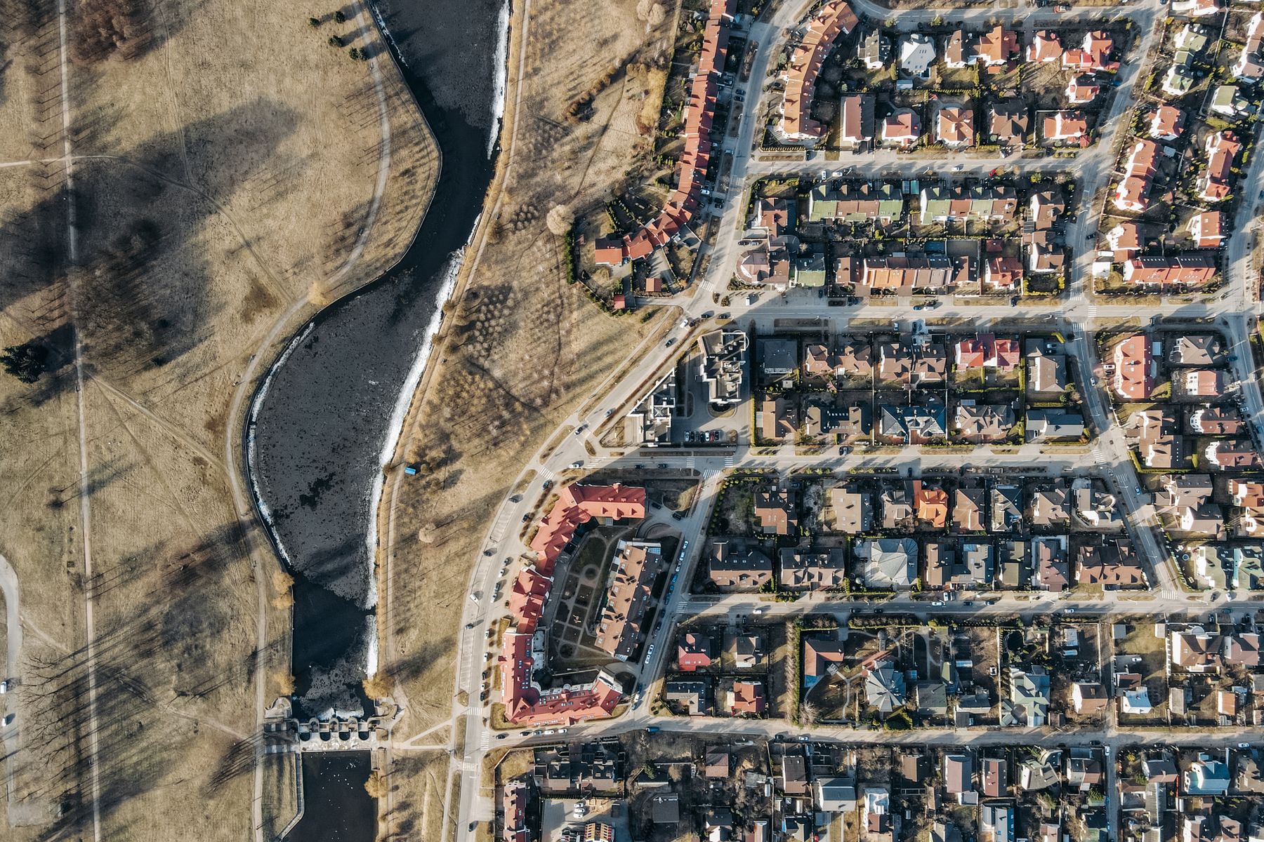 A residential neighborhood beside a river and open green space